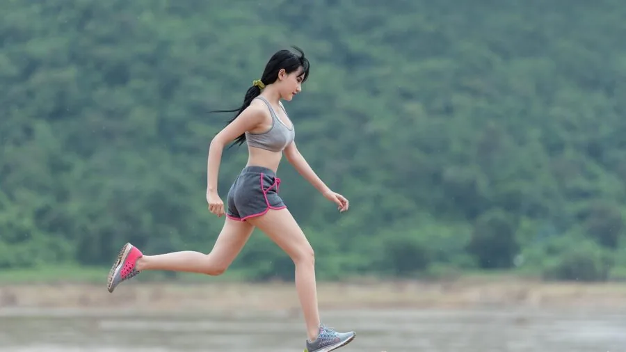 Active person jogging outside while wearing open-ear headphones, experiencing ambient sound awareness during outdoor exercise