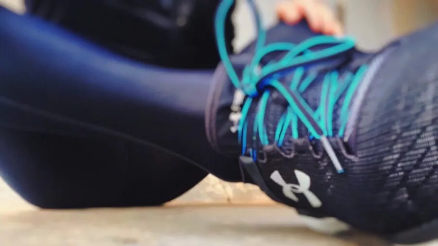Active runner glancing at fitness tracker watch while jogging outdoors on sunny day