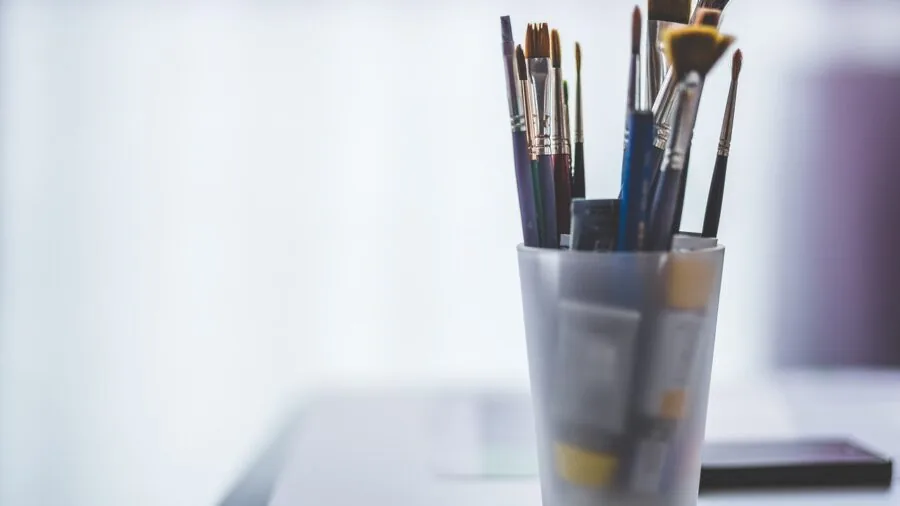 Artist's desk with affordable drawing supplies and sketchbooks in natural lighting