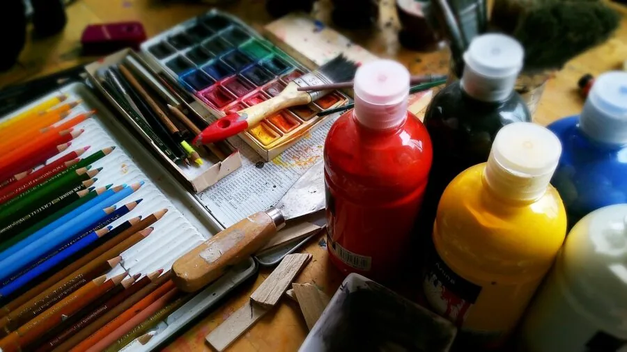 Artist's hand drawing on digital tablet at workspace with creative supplies