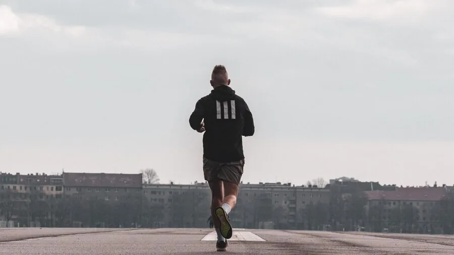 Athletic person running outdoors in hot weather with visible perspiration and determination
