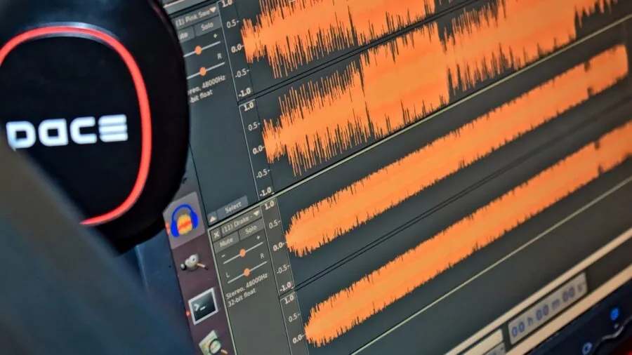 Audio engineer examining sound waveforms on computer monitor in professional studio setting