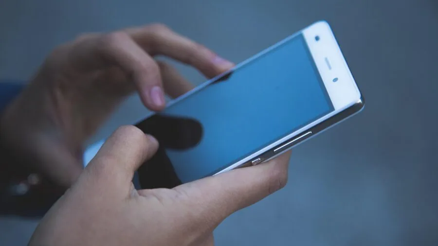 Child checking fitness tracking app on smartphone while wearing activity monitor device