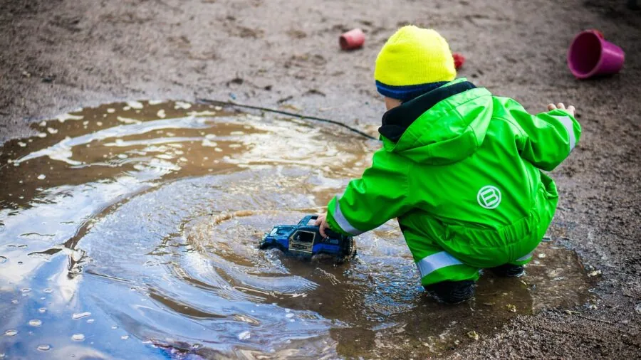 Child splashing in water outdoors, demonstrating need for water-resistant kids smartwatch durability