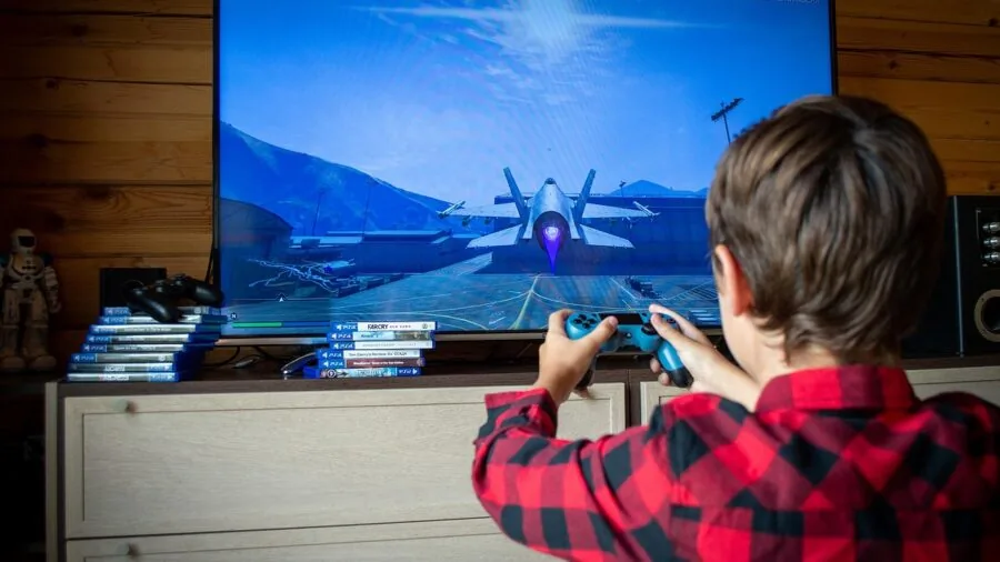 Child thoughtfully choosing from video game collection, examining game cases and making informed decision