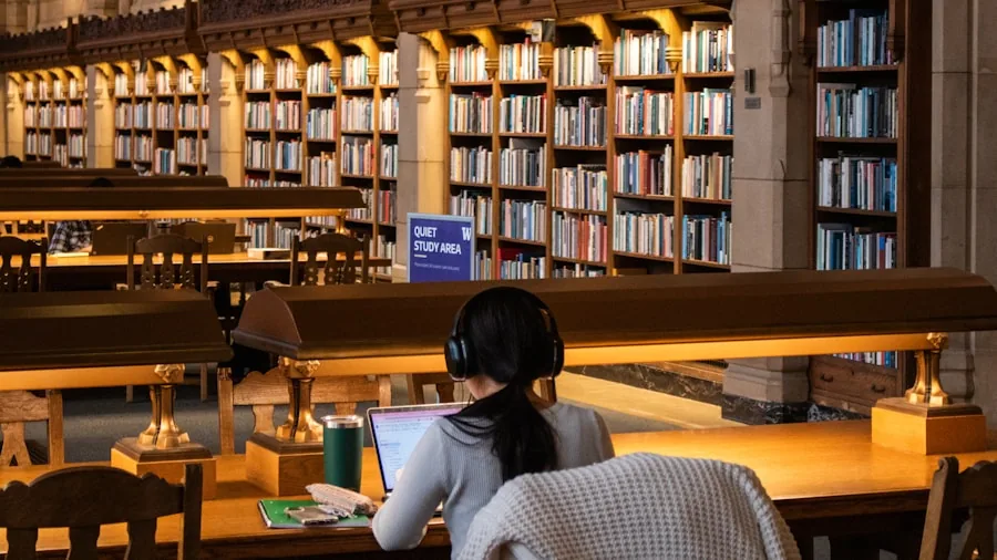 College student studying with laptop in library surrounded by books and learning materials