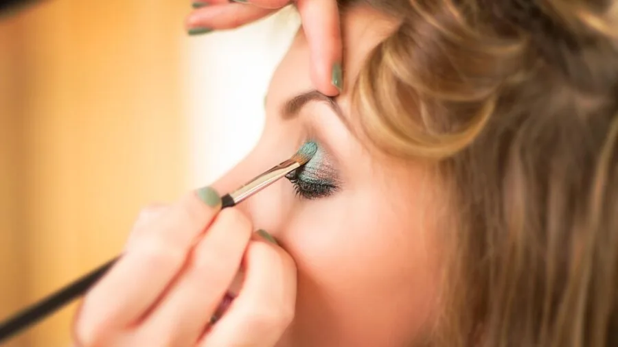 Content creator adjusting ring light position while applying makeup during livestream setup