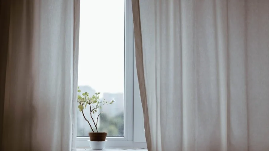 Content creator recording video in dimly lit indoor space with natural window lighting