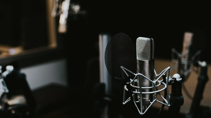 Content creator speaking into microphone at home recording setup with acoustic treatment visible
