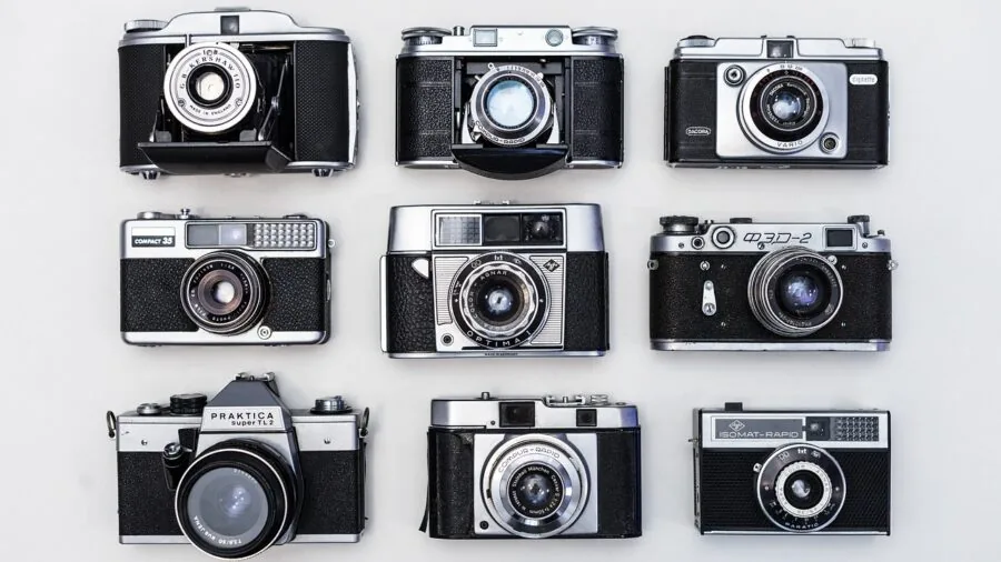 Creative professional arranging various camera lenses on wooden desk in natural light
