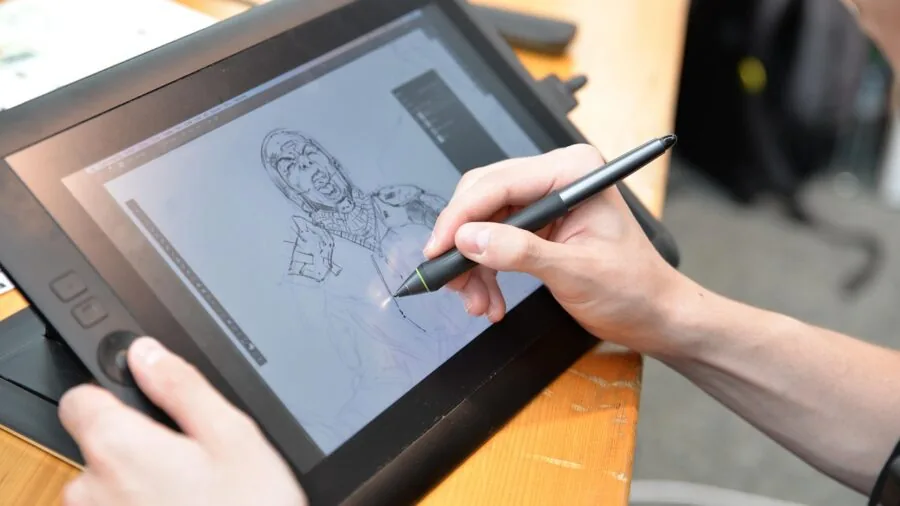 Creative professional sketching on digital display with stylus in natural workspace