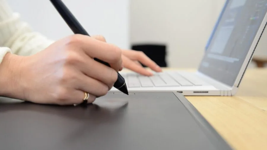 Creative professional working on digital illustration with stylus and display tablet at desk