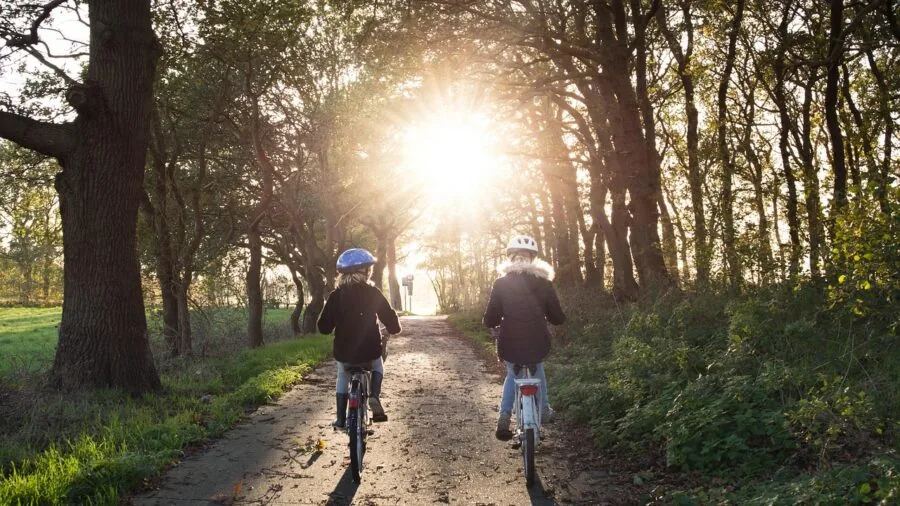 Cyclist adjusting helmet strap while riding on outdoor trail path