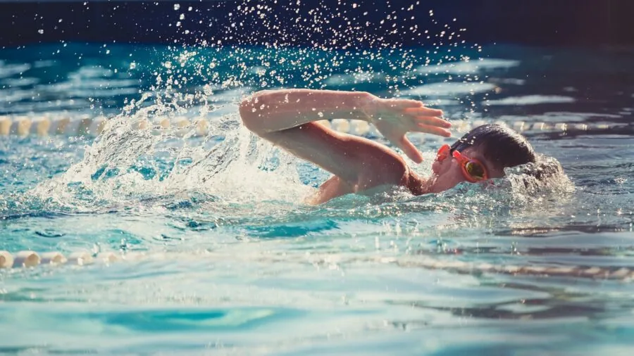 Family enjoying summer day at outdoor pool with children playing in water
