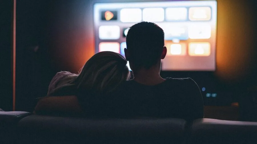 Family gathered in living room watching TV together in warm evening lighting