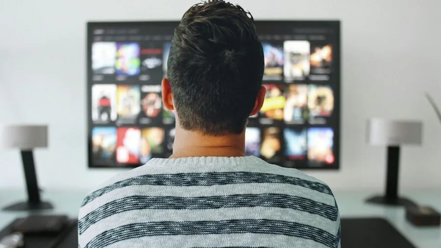 Family gathered in living room watching TV together on couch, discussing viewing options
