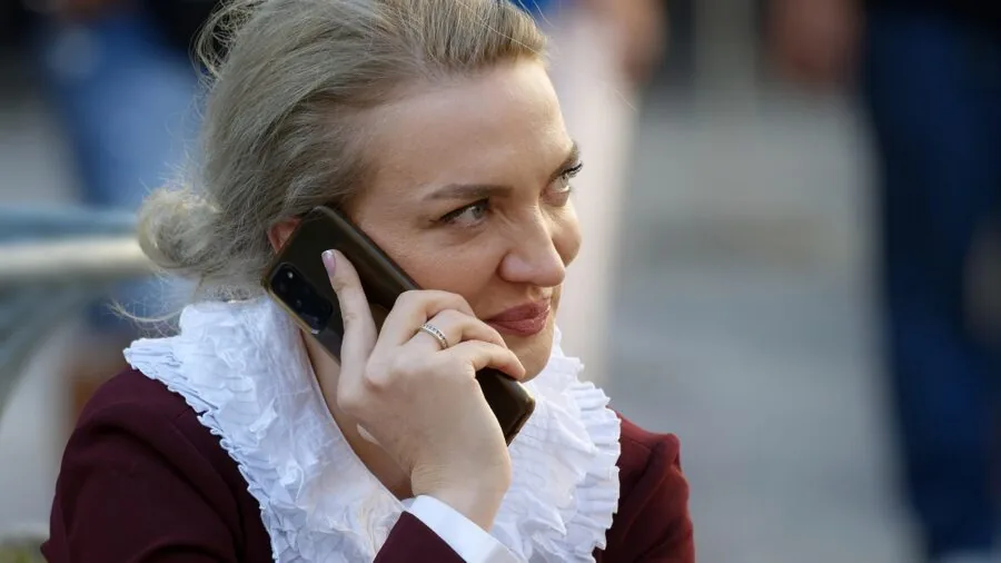 Female jogger speaking on phone during outdoor run on sunny path