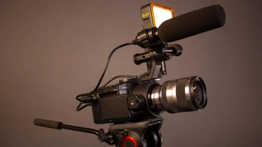 Filmmaker operating professional camera equipment during video production shoot outdoors