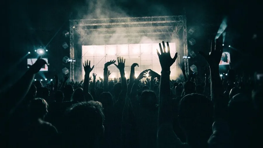 Friends enjoying music and dancing at an outdoor nighttime party with festive lighting