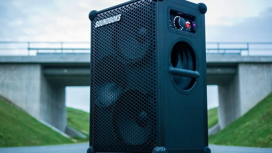 Friends enjoying music at an outdoor gathering with portable audio equipment in natural lighting