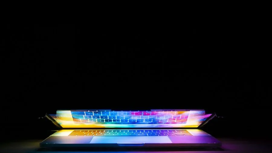 Gamer focused on laptop display showing vibrant colors during gameplay session
