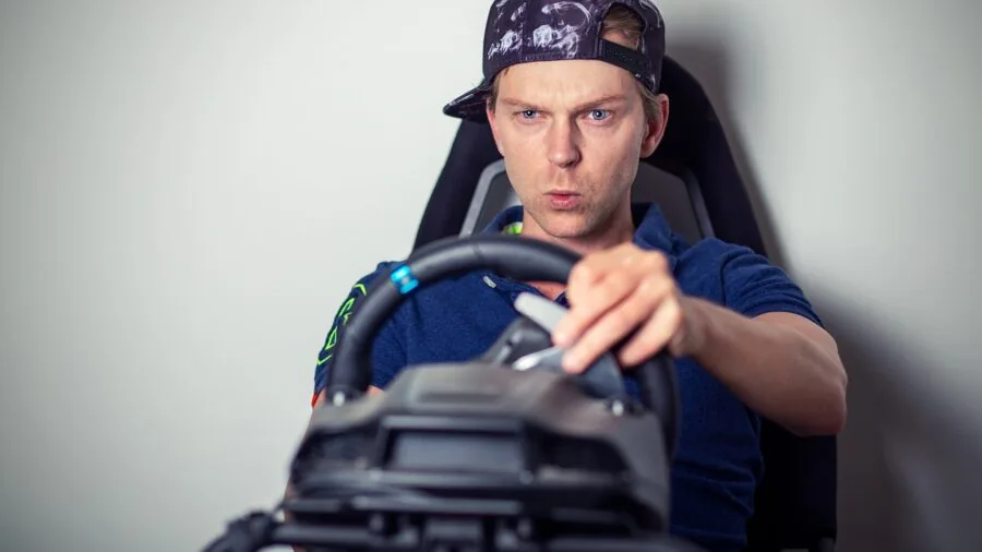 Gamer immersed in racing simulator with steering wheel controller in dedicated home setup