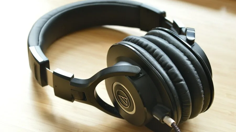 Gamer wearing headphones during PS5 gaming session in room with console and controller