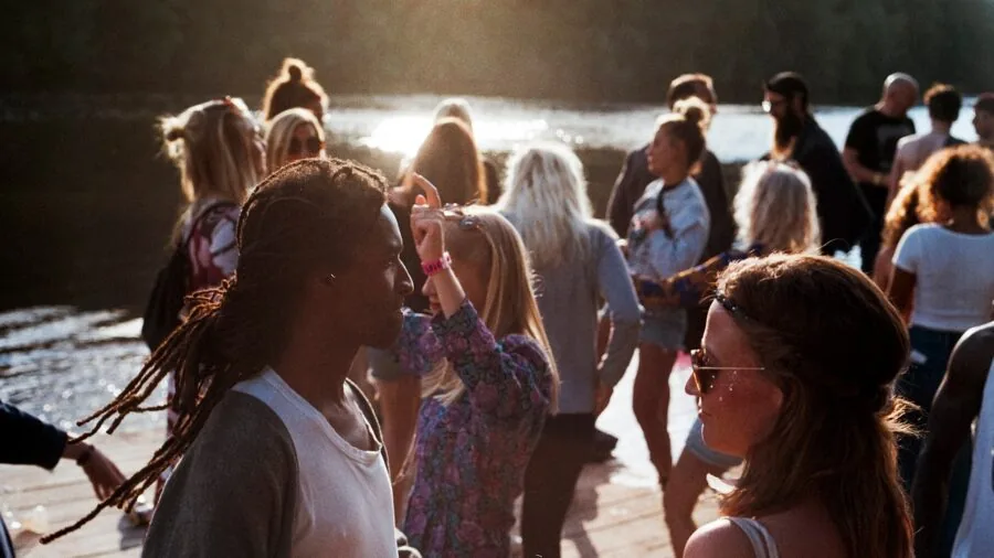 Group of friends dancing together at an outdoor evening party with warm lighting
