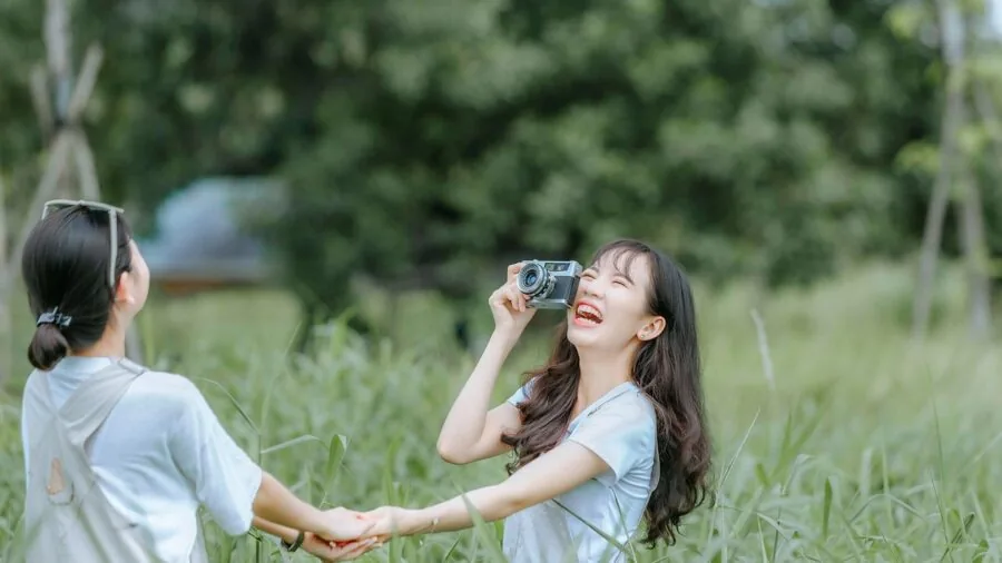 Group of friends laughing while holding and viewing instant film photographs at a casual gathering