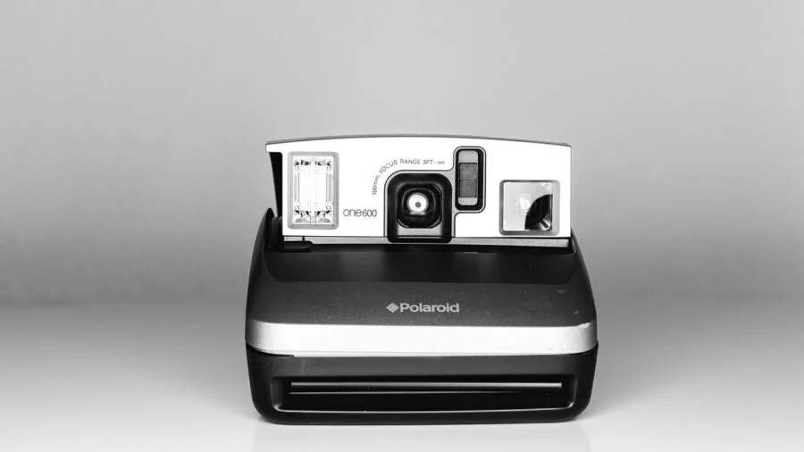 Group of friends laughing while looking at instant camera photos they just took outdoors