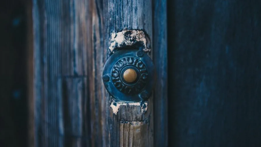 Homeowner installing a doorbell on residential front door frame with tools