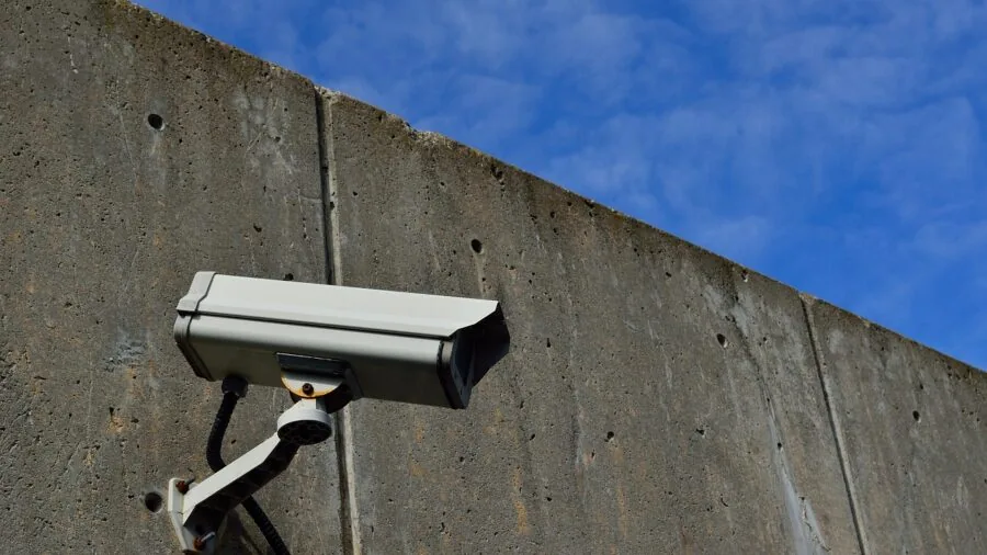 Homeowner installing weatherproof security camera on exterior house wall for protection
