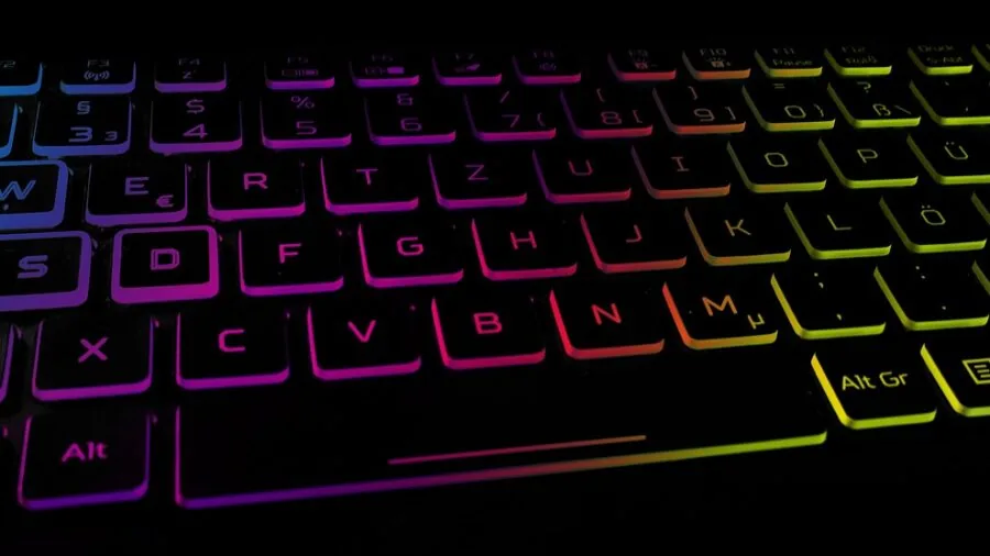 Modern gaming desk setup with illuminated PC components and ambient RGB lighting in dark room