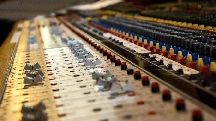 Music producer working at computer desk with microphone and audio equipment in professional home studio