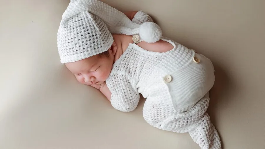 Parent checking baby monitor app on smartphone while infant sleeps peacefully in crib at home