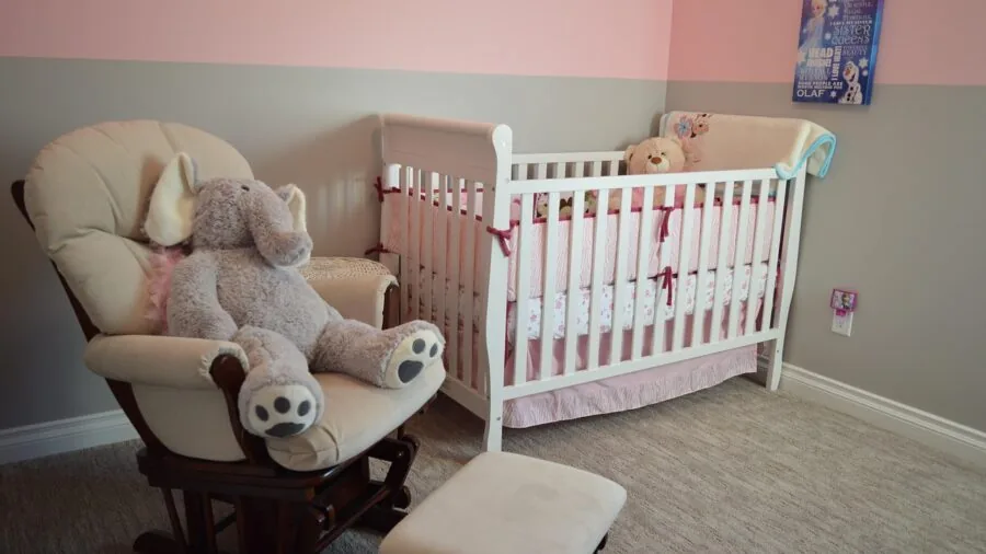Parent checking on sleeping baby in nursery room through monitor device