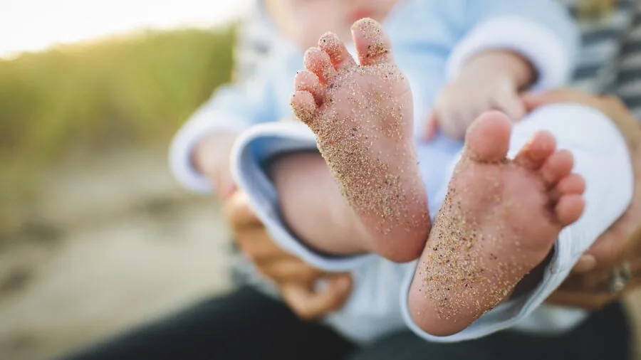 Parent checking smartphone app while sitting near sleeping infant in nursery