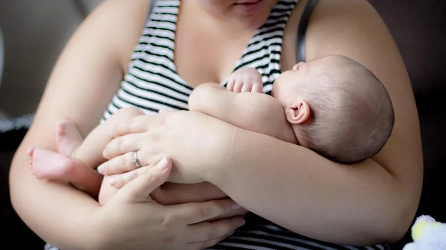 Parent watching baby monitor display while child sleeps in nursery bedroom