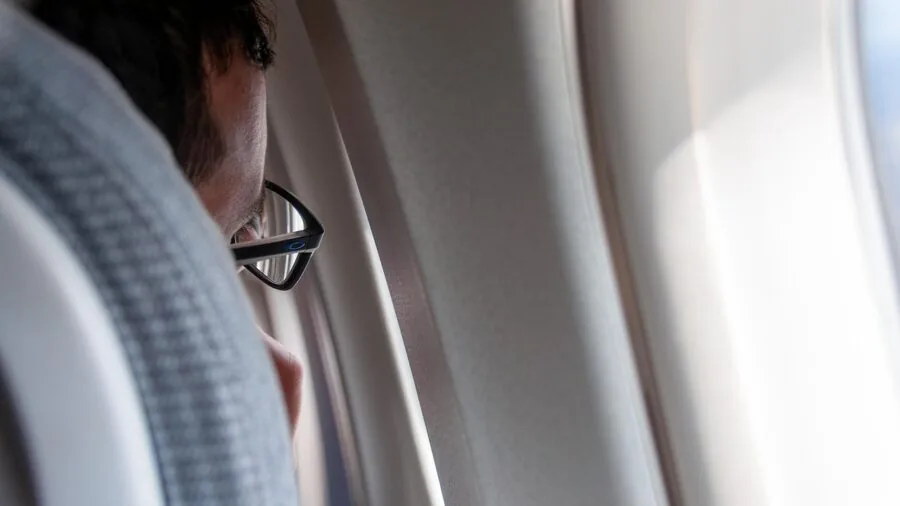 Passenger wearing comfortable headphones sleeping peacefully on long-haul flight near window