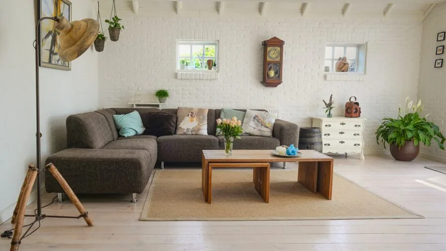 Person adjusting elevated speakers at ear level in a home audio setup with comfortable seating