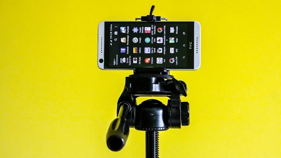 Person adjusting phone holder on tripod for content creation in bright studio environment