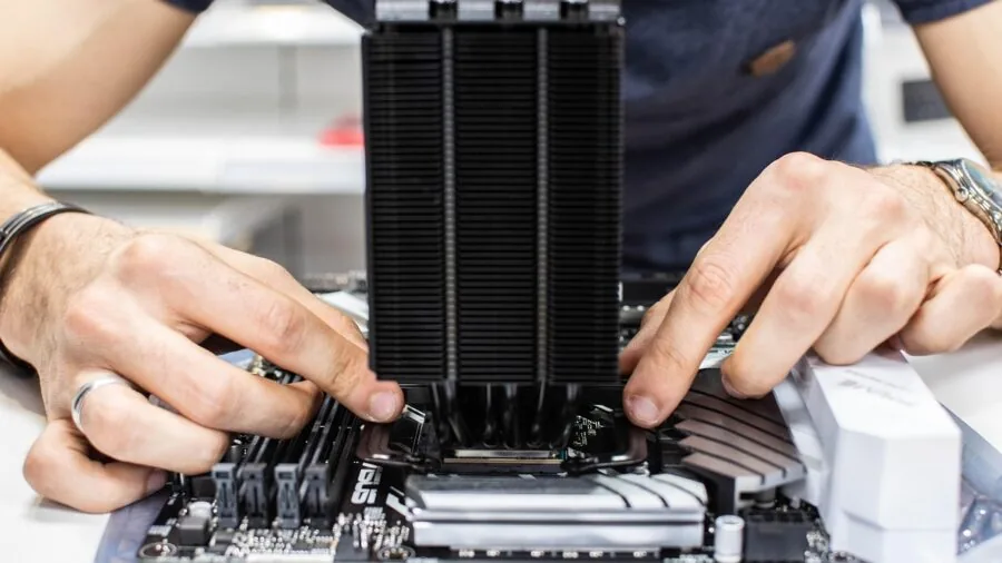 Person assembling PC components with tower CPU cooler and RAM modules in custom computer build setup
