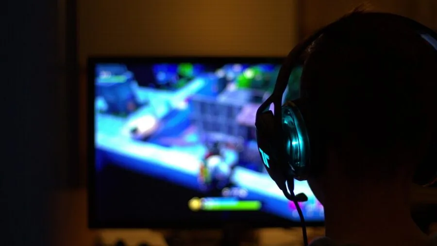Person at desk streaming video games with professional lighting and multiple monitors for gaming content creation