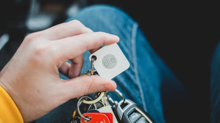 Person attaching small tracker device to keyring on bag, practical everyday carry setup