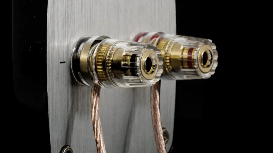 Person carefully connecting audio cables to speaker binding posts during home audio setup