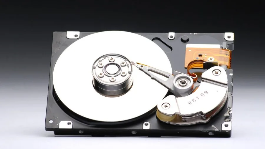Person carefully managing computer files and data organization on desk with multiple devices