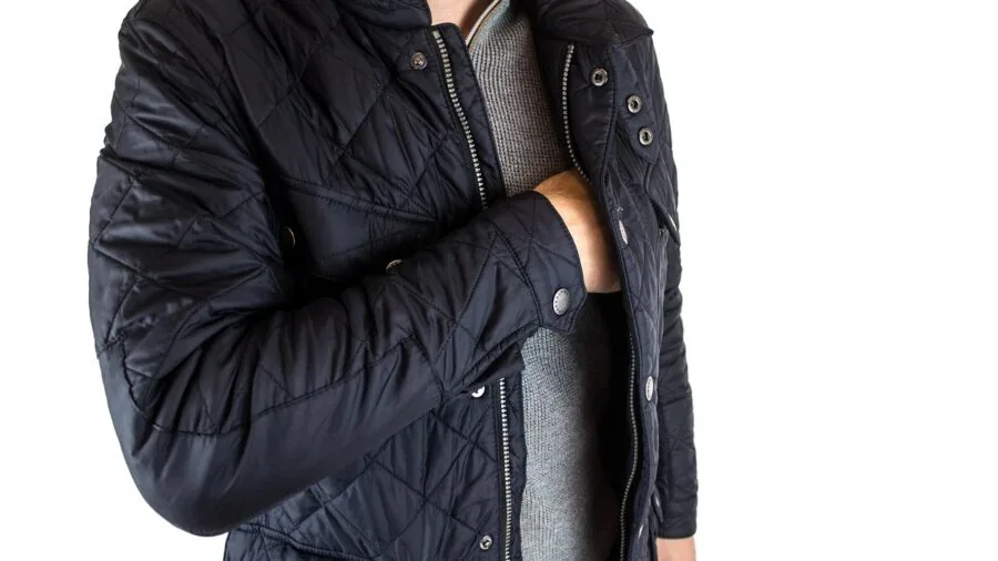 Person carrying compact speaker in jacket pocket while outdoors, demonstrating portability and convenience