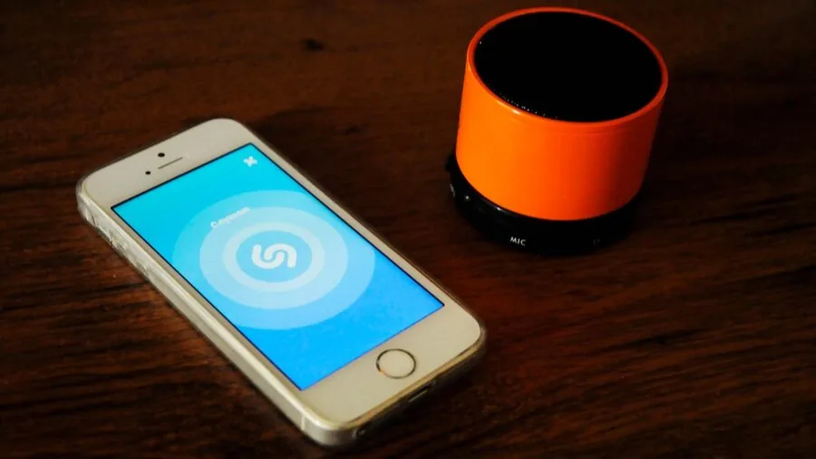 Person carrying compact speaker on hiking trail through forest during daytime adventure