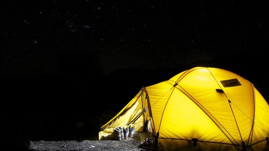 Person charging electronics at campsite with solar power setup during outdoor adventure