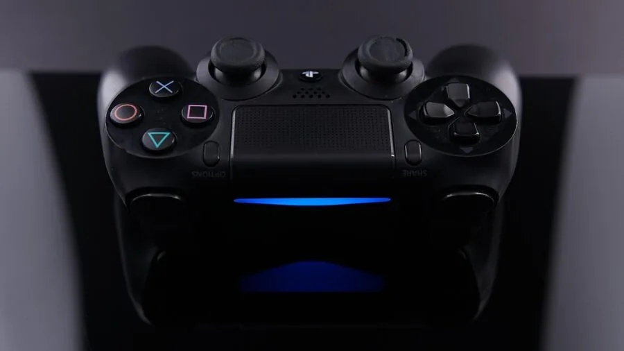 Person charging gaming controller with laptop setup during gaming session